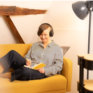 Podcast hören Bettina Mathar auf gelbem Sofa